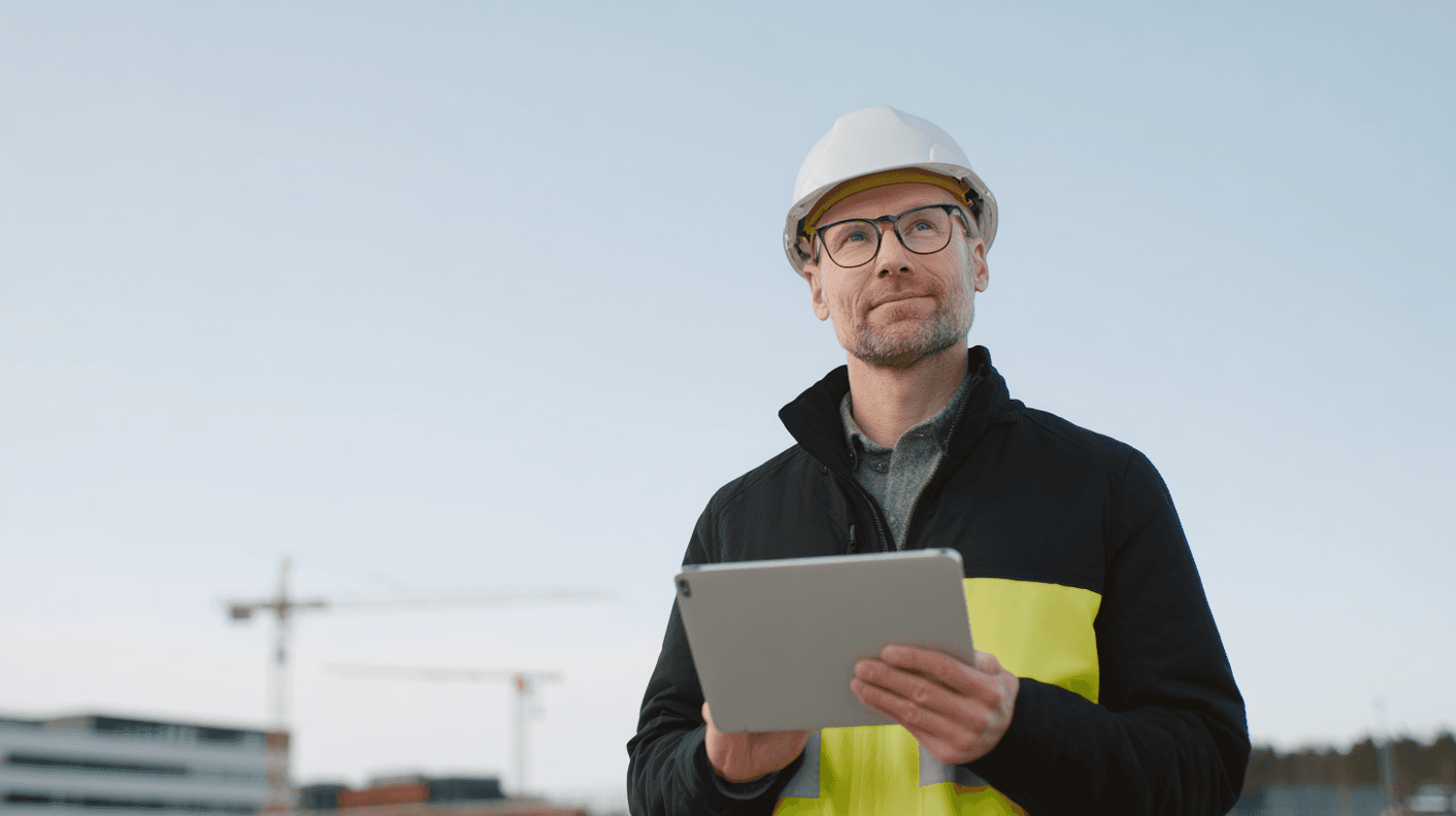 Roofing project manager in a hard hat reviewing an inspection on a tablet