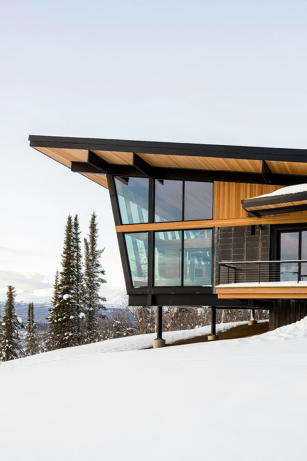 Modern mountain home with a long overhanging metal roof in the snow